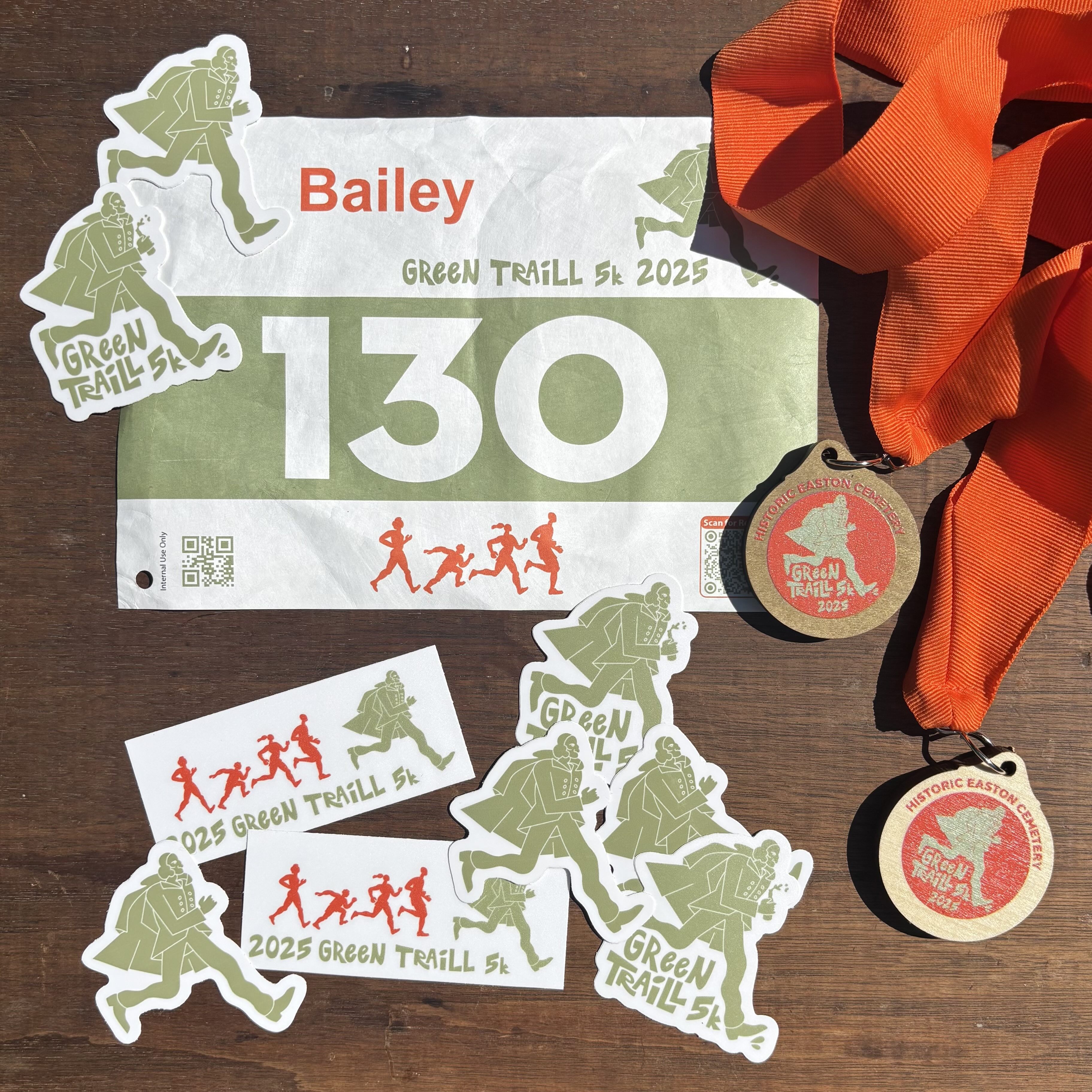green trail items - a race bib, two race medals, and an assortment of stickers