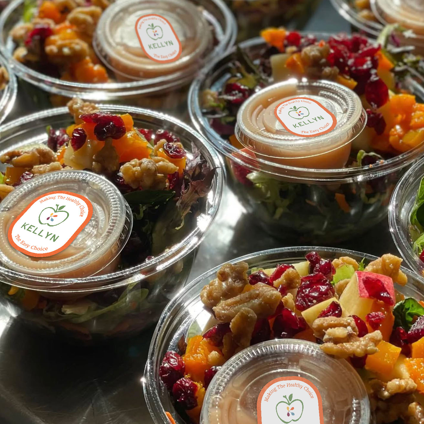 an array of salads prepared by kellyn in individual containers with a kellyn sticker on top (mockup)